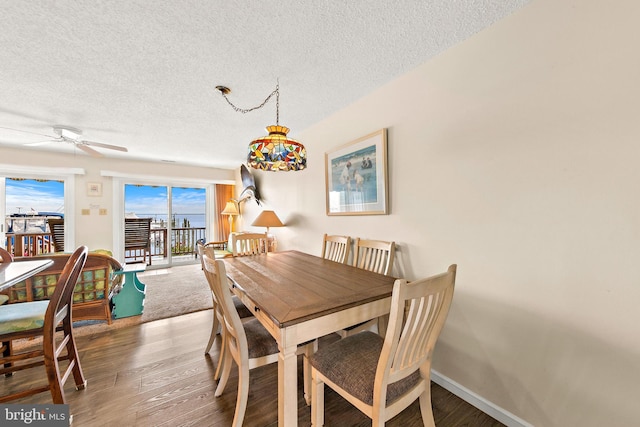 dining area with ceiling fan, hardwood / wood-style flooring, and a textured ceiling