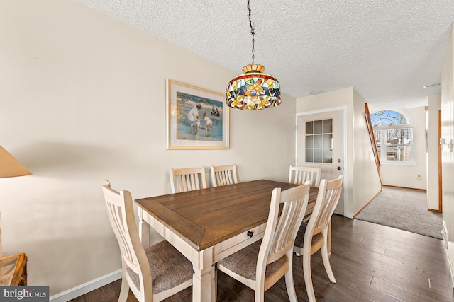 dining space featuring dark carpet and a textured ceiling