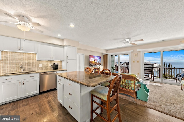 kitchen with sink, backsplash, stainless steel dishwasher, dark hardwood / wood-style floors, and white cabinetry