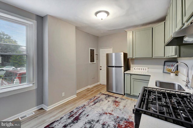 kitchen featuring range with gas cooktop, sink, stainless steel fridge, green cabinetry, and light hardwood / wood-style flooring