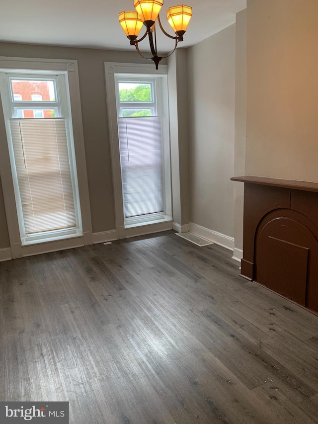 unfurnished dining area with a notable chandelier, plenty of natural light, and dark hardwood / wood-style flooring