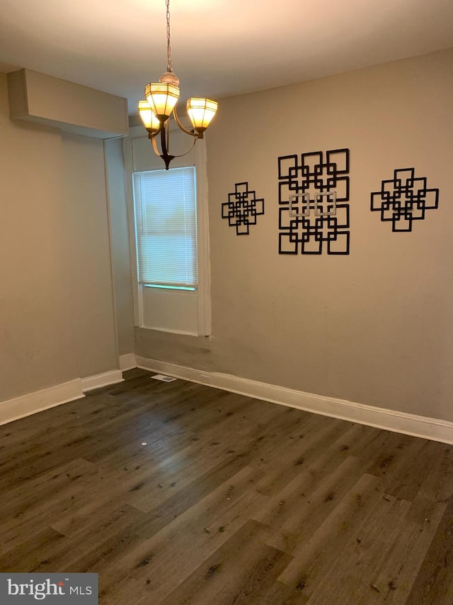 unfurnished dining area featuring an inviting chandelier and dark hardwood / wood-style flooring