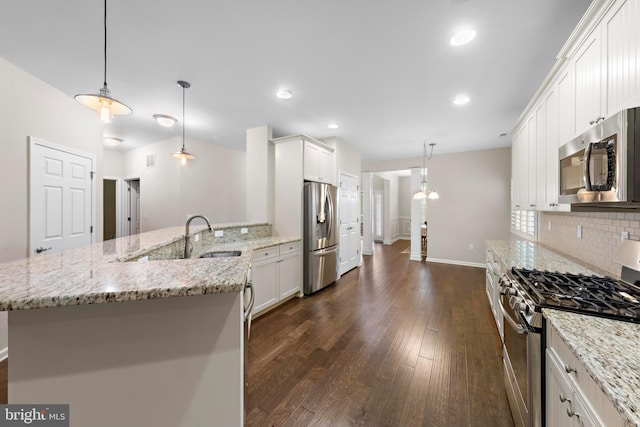 kitchen featuring appliances with stainless steel finishes, white cabinets, decorative light fixtures, sink, and light stone counters