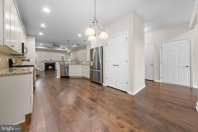 kitchen with ceiling fan, light stone countertops, white cabinetry, pendant lighting, and stainless steel appliances