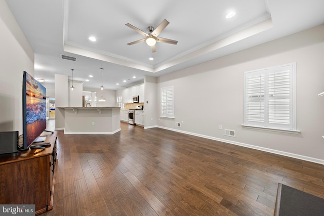 living room featuring ceiling fan, dark hardwood / wood-style floors, a tray ceiling, and ornamental molding