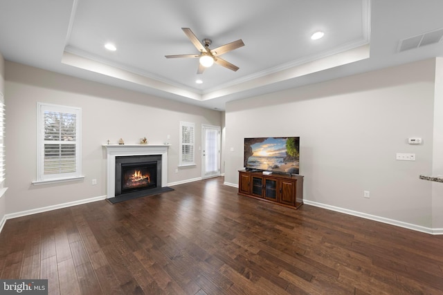 unfurnished living room featuring a raised ceiling, ornamental molding, and dark wood-type flooring