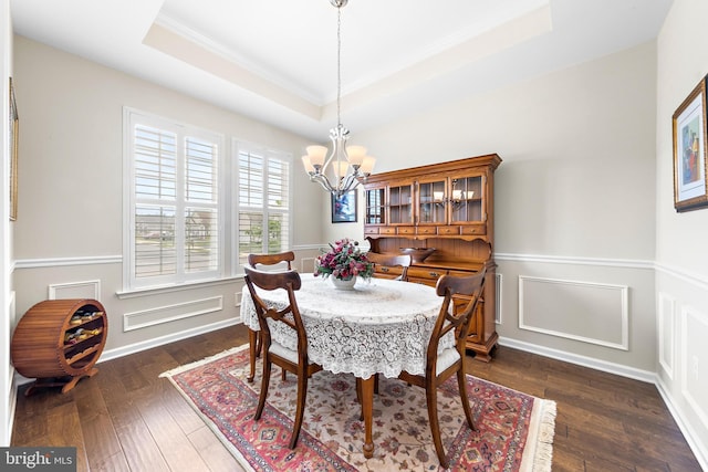 dining space featuring crown molding, dark wood-type flooring, a tray ceiling, and an inviting chandelier