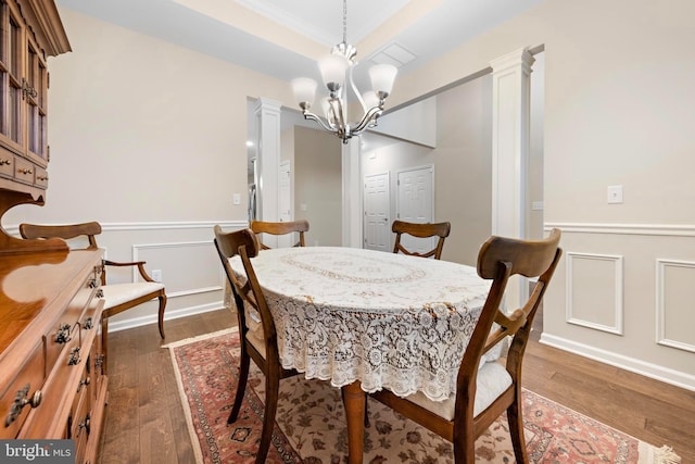 dining area with decorative columns, dark wood-type flooring, crown molding, and an inviting chandelier