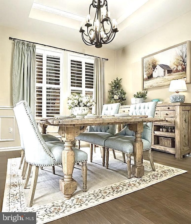 dining space with a chandelier, a raised ceiling, ornamental molding, and dark hardwood / wood-style floors