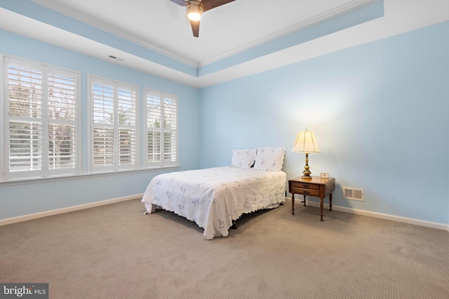 carpeted bedroom with ceiling fan, a raised ceiling, and ornamental molding