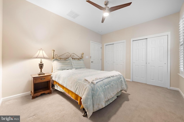 carpeted bedroom featuring multiple closets and ceiling fan