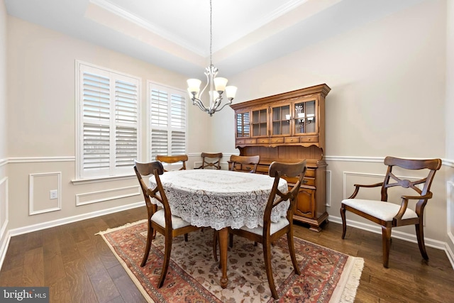 dining area featuring a chandelier, a raised ceiling, and dark hardwood / wood-style flooring