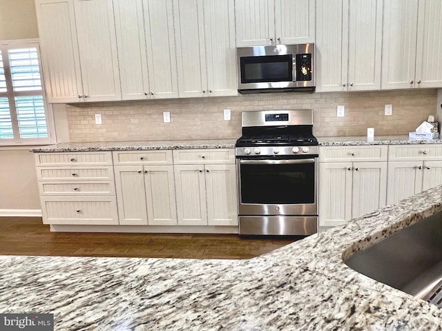 kitchen featuring white cabinets, light stone counters, appliances with stainless steel finishes, and dark hardwood / wood-style flooring