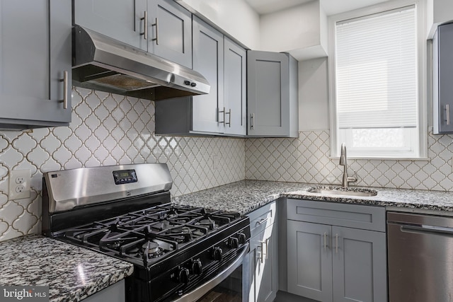 kitchen with sink, tasteful backsplash, dark stone counters, gray cabinets, and stainless steel appliances