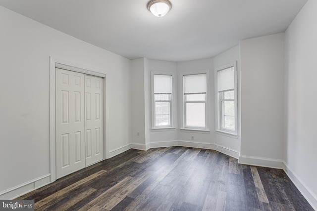 unfurnished bedroom featuring dark wood-type flooring and a closet