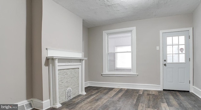 unfurnished living room featuring dark wood-type flooring and a textured ceiling