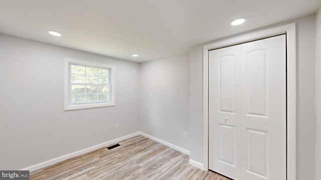 unfurnished bedroom with light wood-type flooring and a closet