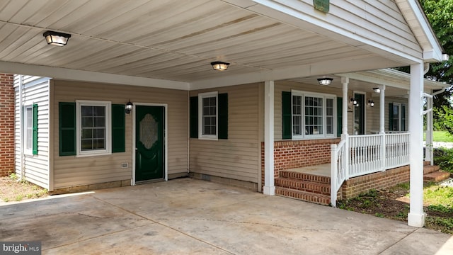 view of exterior entry with a porch and a carport