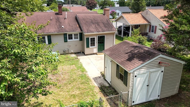 back of property featuring a lawn and a storage shed