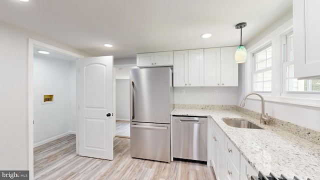 kitchen featuring light stone countertops, pendant lighting, white cabinets, stainless steel appliances, and sink