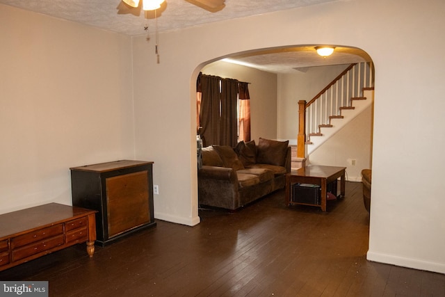 living room with ceiling fan, dark hardwood / wood-style flooring, and a textured ceiling