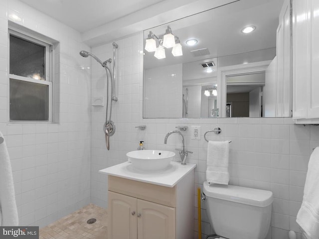 bathroom with toilet, vanity, tile walls, and tiled shower