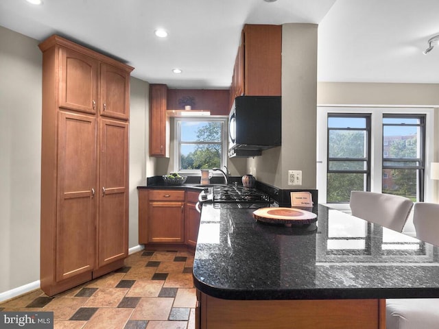 kitchen with plenty of natural light, sink, kitchen peninsula, and dark stone counters