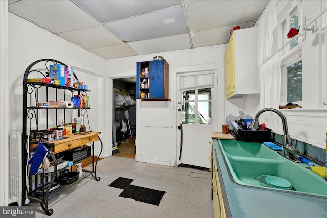 kitchen featuring radiator heating unit, sink, a drop ceiling, and light tile patterned floors