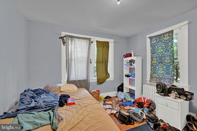 bedroom featuring radiator heating unit and hardwood / wood-style flooring