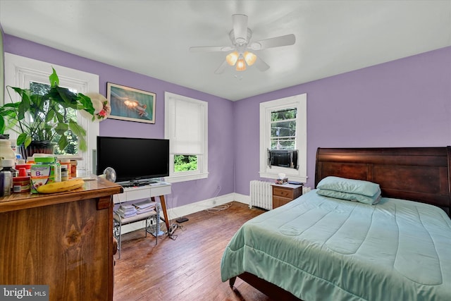 bedroom with dark wood-type flooring, radiator, and ceiling fan