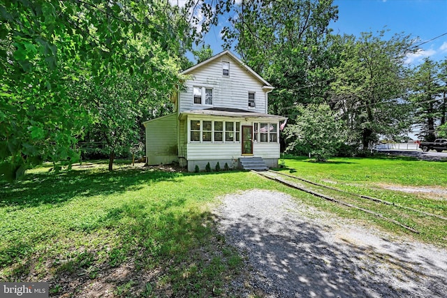 view of property with a sunroom and a front lawn