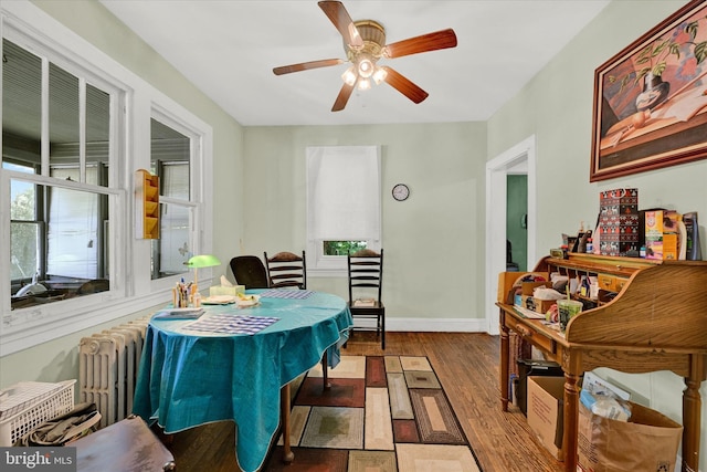 office area featuring radiator heating unit, ceiling fan, and dark wood-type flooring