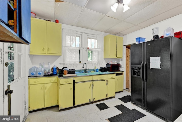 kitchen featuring sink, black fridge, a drop ceiling, and light tile patterned floors