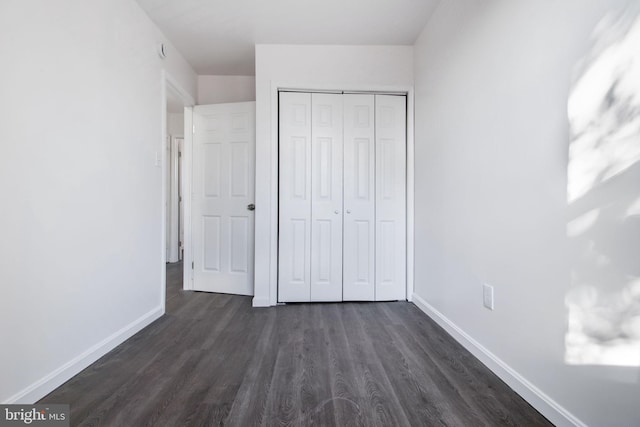 unfurnished bedroom with a closet and dark hardwood / wood-style floors