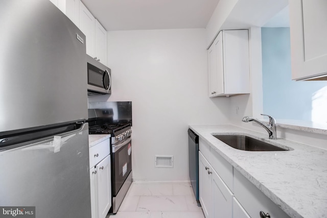 kitchen with light stone countertops, sink, white cabinetry, and stainless steel appliances