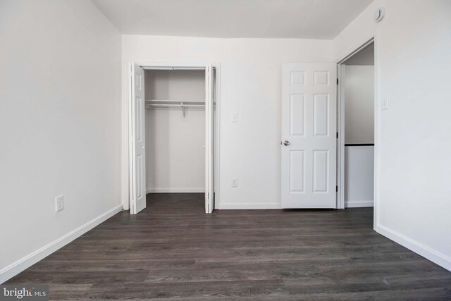 unfurnished bedroom featuring dark hardwood / wood-style floors and a closet