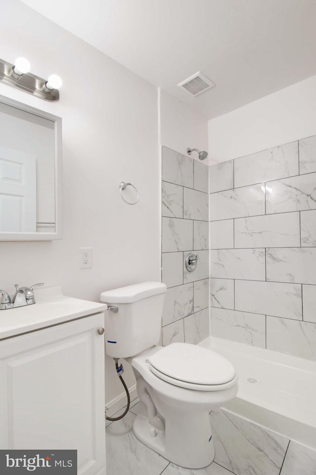 bathroom with toilet, vanity, and tiled shower