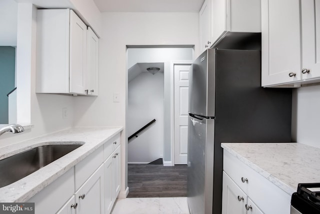 kitchen featuring light stone countertops, sink, and white cabinets