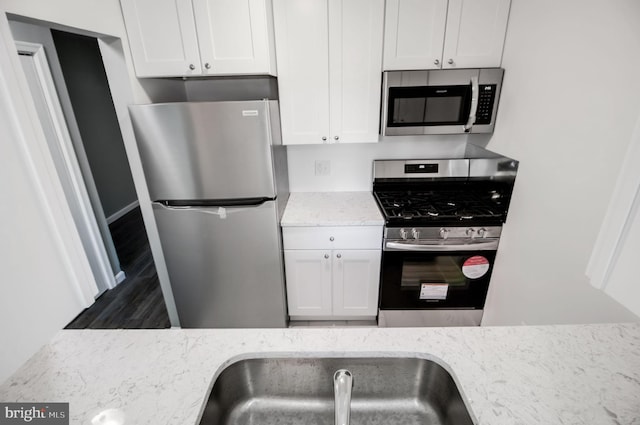 kitchen with light stone countertops, appliances with stainless steel finishes, and white cabinetry