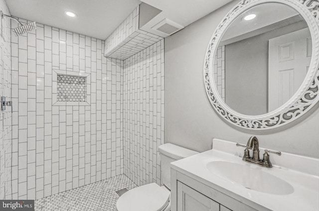 bathroom featuring vanity, toilet, and a tile shower