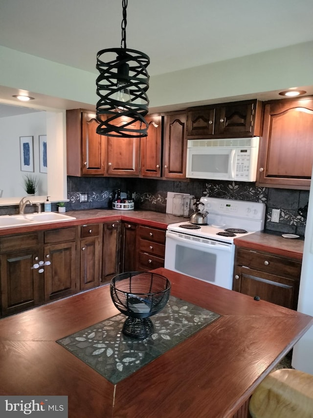 kitchen featuring tasteful backsplash, sink, hanging light fixtures, hardwood / wood-style flooring, and white appliances