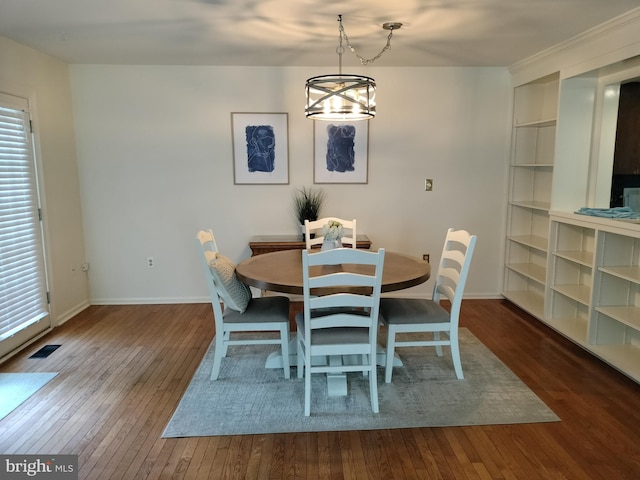 dining area with dark wood-type flooring and an inviting chandelier