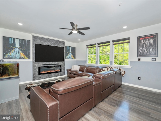 living room featuring ceiling fan, hardwood / wood-style floors, and a stone fireplace