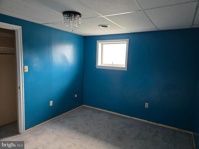 unfurnished bedroom featuring a closet, carpet, and a drop ceiling