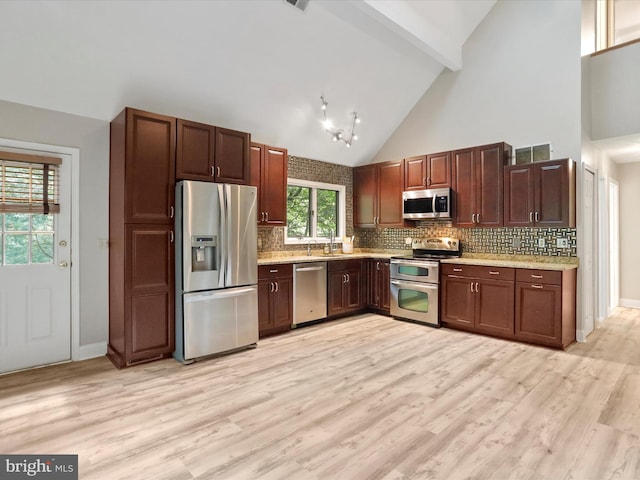 kitchen featuring backsplash, stainless steel appliances, high vaulted ceiling, and light hardwood / wood-style floors