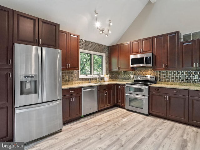 kitchen with appliances with stainless steel finishes, backsplash, light hardwood / wood-style floors, and sink