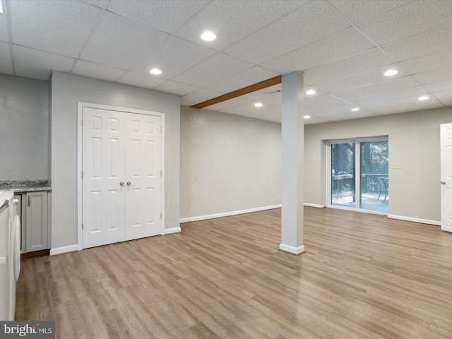 basement featuring a drop ceiling and light hardwood / wood-style floors