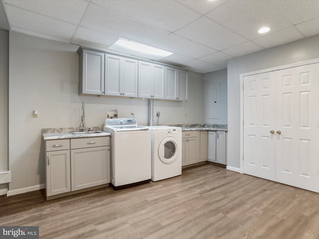 laundry room featuring light hardwood / wood-style flooring, cabinets, sink, and separate washer and dryer