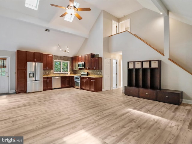 kitchen featuring high vaulted ceiling, light hardwood / wood-style flooring, appliances with stainless steel finishes, and a skylight