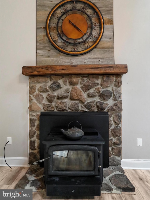 room details with a fireplace, hardwood / wood-style floors, wood walls, and a wood stove